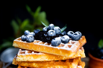 Waffles with fresh blueberries and powdered sugar on the rustic table. Freshly made Belgian waffles