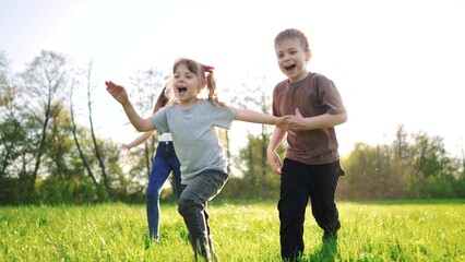 Fototapeta premium group of children running in the park. happy family baby kid dream concept. kindergarten. children hands to the sides play pilots plane run on the grass lifestyle in the summer in the park