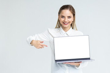 Naklejka premium Business woman smile sitting at the desk looking at camera, point finger at isolated white laptop screen over white background