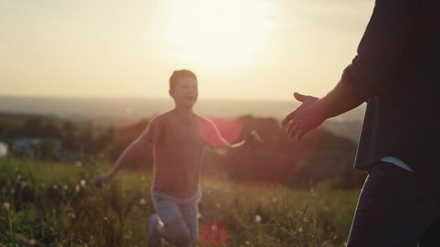 Little boy running for dad at the meadow during the sunset. Shot with RED helium camera in 4K.  