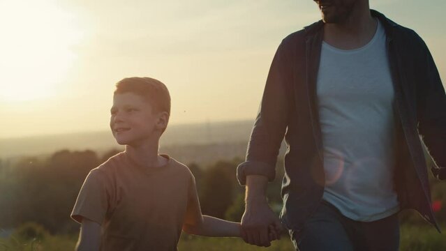 Little boy walking with dad at the meadow during the sunset. Shot with RED helium camera in 4K. 