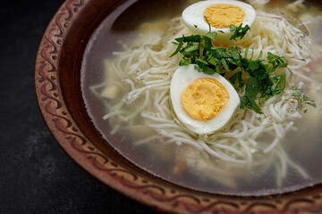 Chicken broth, with noodles, herbs and egg, studio light