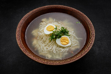 Chicken broth, with noodles, herbs and egg, studio light