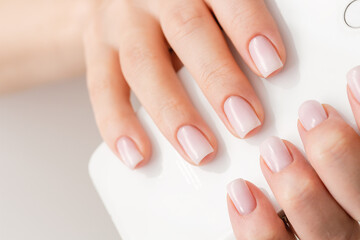 Female hands with beautiful nails with stylish trendy nude manicure.
