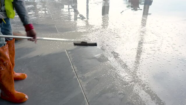 4K, Medium shot of the bottom of the foot of a construction worker using a plastic sap to repel water. Clean the cement floor that is filled with dirty water from working on the construction site.