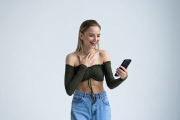 Naklejka premium Portrait of a shocked young woman looking at mobile phone isolated over white background