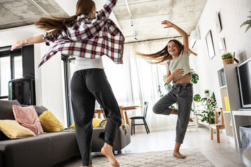Mother and daughter dancing and having fun in the living room.