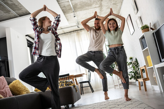 Parents with their daughter doing yoga and exercise early in the morning at home.