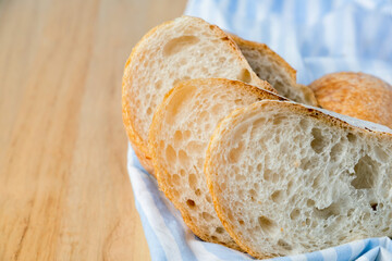 Fresh sliced baguette bread on wooden table. Healthy eating breakfast.