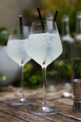 transparent cocktail with two straws in a glass with a stem on a wooden surface