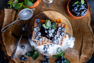 Waffles with fresh blueberries and powdered sugar on the rustic table. Freshly baked Belgian waffles