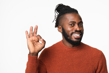 Happy smiling african-american young man with dreadlocks wearing red sweater showing okay gesture isolated in white background