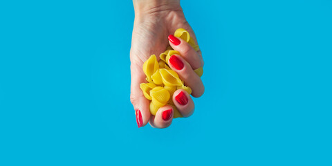 pasta Conchiglie in a female hand. high calorie food. calorie product. extra calories. Banner for insertion into site. Place for text cope space. Horizontal image.