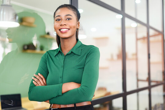 Portrait of confident African-American businesswoman standing with arms crossed, purposeful multiracial female office employee in smart casual wear looking at the camera and smiles