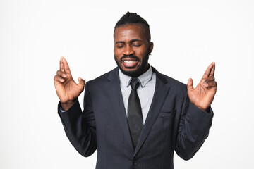 African-american young businessman leader ceo boss bank employee manager crossing fingers with eyes closed for good luck, placing bets isolated in white background