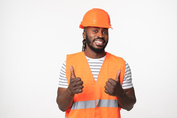 Happy african-american young man engineer construction worker architect in orange reflective vest and hardhat looking at camera showing thumb up isolated in white background