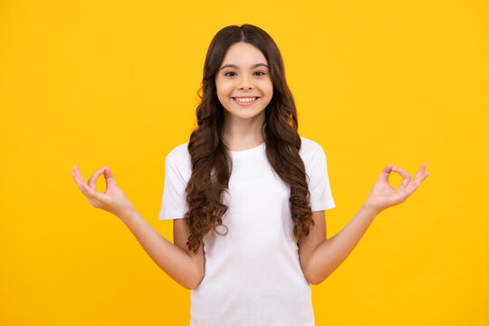 Happy teenager, positive and smiling emotions of teen girl. Teenager child in white shirt hold hands in yoga om aum gesture relax meditate try calm, isolated on yellow background.