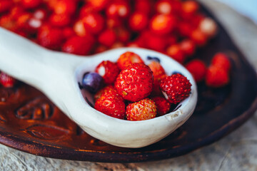 wild strawberries with blueberry  in a spoon, forest red berries, wood style, farming