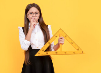thinking teen girl in uniform and glasses hold mathematics triangle for measuring, measurement.