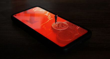 Business man figure standing on a smartphone with a picture of bitcoins.
