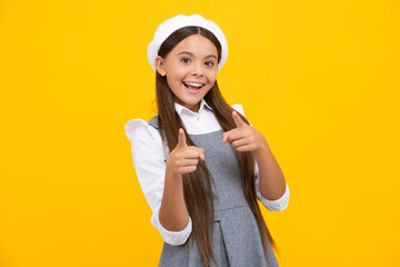 Happy teenager, positive and smiling emotions. Cheerful teen child posing isolated over yellow background pointing to you. Happy girl face, positive and smiling emotions.