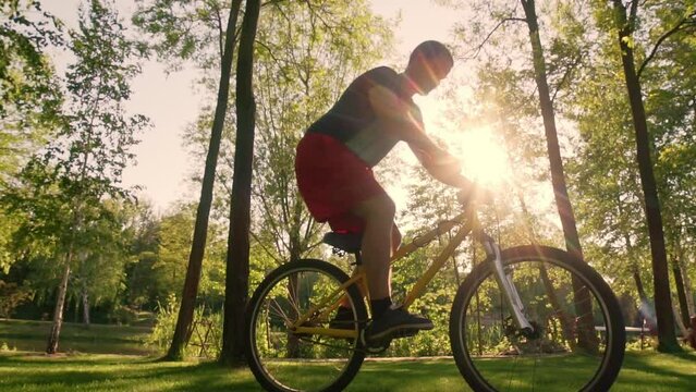 Cyclist slow jumps on the rear wheel against the background of the sun.