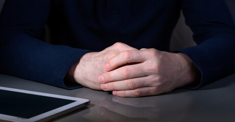 Fototapeta premium The hands of a mature businessman with a tablet in dark colors