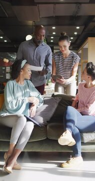 Vertical video of diverse business people discussing work during meeting at office