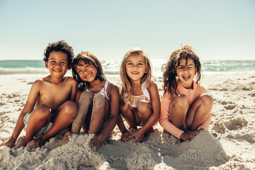 Cute kids sitting in sea sand at the beach