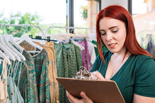 Young Businesswoman, Writing In The Folder, Writing Down Sales Prices. Woman Owner Of A Small Business Taking Inventory. Concept Of Work And Business.