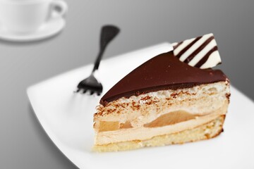 Homemade chocolate cheesecake slice in white plate on cafe background