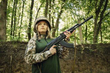 Fototapeta premium Portrait of a Ukrainian military woman with with assault rifle Akm