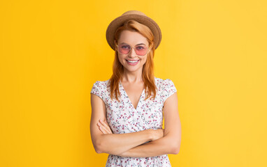happy woman in straw hat and sunglasses on yellow background. crossed hands