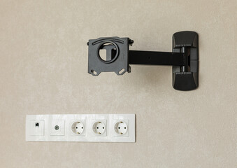 Black metal TV mount on the wall. Multifunctional socket with internet and TV access