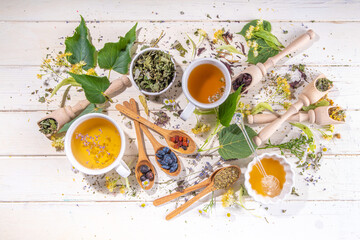 Obraz na płótnie Canvas Healthy drinks, harvest herbs and flowers concept. Fresh and dried organic herbal, set of different floral tea variations, with brewed hot tea cups on white wood table copy space