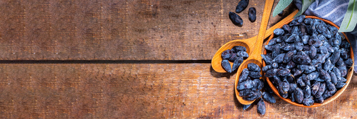 Bowl with fresh  raw farm haskap berry, garden grown honeysuckle, honeyberry, on wooden background copy space