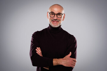 Portrait of handsome man wearing eyewear and turtleneck sweater while standing at isolated grey background