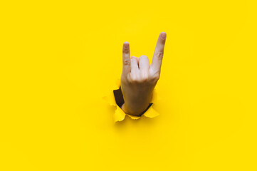 A woman's hand shows a rock and roll gesture, a party, a goat on a yellow background with a torn...