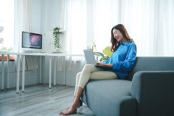 girl sitting on the sofa at home working on the computer. beautiful smile