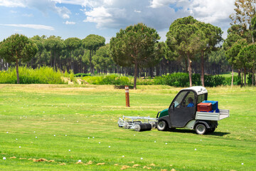 Golf course and golf cart collecting golf balls. Ballpicker on driving range of golf club