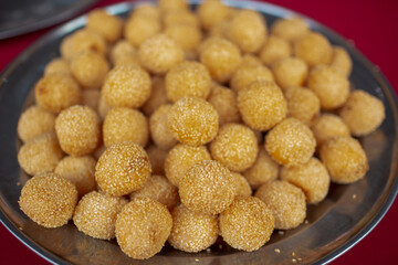 A plate full of sesame seed dessert balls ready to be eaten. It is filled with red bean paste and popular in Malaysia