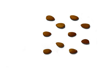 On a white background lies a large number of almonds. Ripe and delicious almonds. Almonds are brown in color. Each nut lies separately.