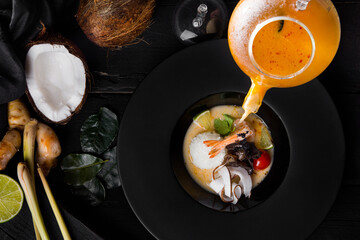 The broth in a jug is poured into a plate with rice, shrimps, lime, tomatoes