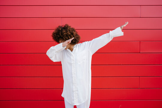 Young woman doing dab in front of red wall