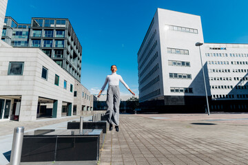 Businesswoman jumping at financial district on sunny day