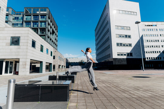 Young businesswoman jumping on footpath at financial district