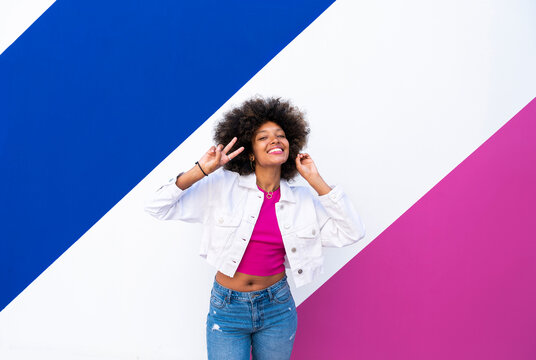 Smiling woman gesturing and standing in front of colorful wall