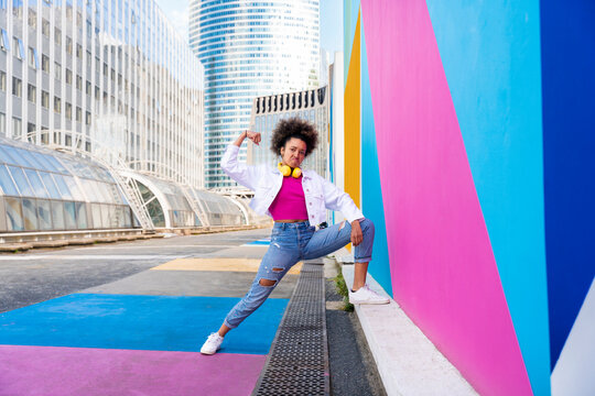 Afro woman flexing muscles by colorful wall