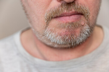 Obraz premium The lower part of the man's face. Calm Mature man with stubble. Gray hair on beard and mustache. The bottom of the man's face. Selective focus.