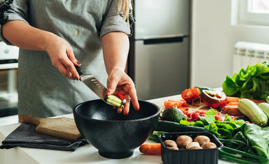 Close Up Photo of Woman Hands Putting Sliced Cucumber in a Salad Bowl on a Kitchen Desk